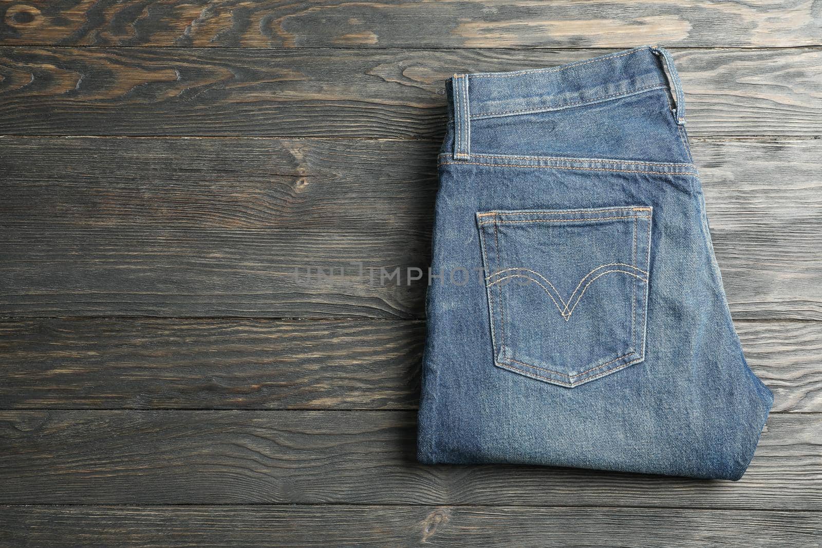 Blue jeans folded on a wooden background, space for text by AtlasCompany