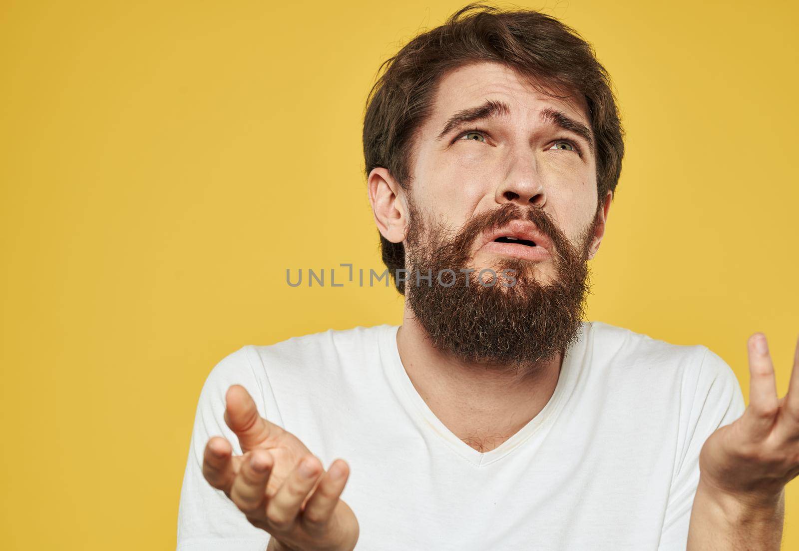 Upset guy crying on a yellow background and gesturing with his hands. High quality photo