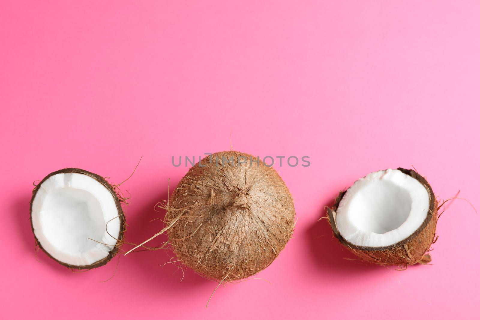 Two coconut one of which split on color background, space for text