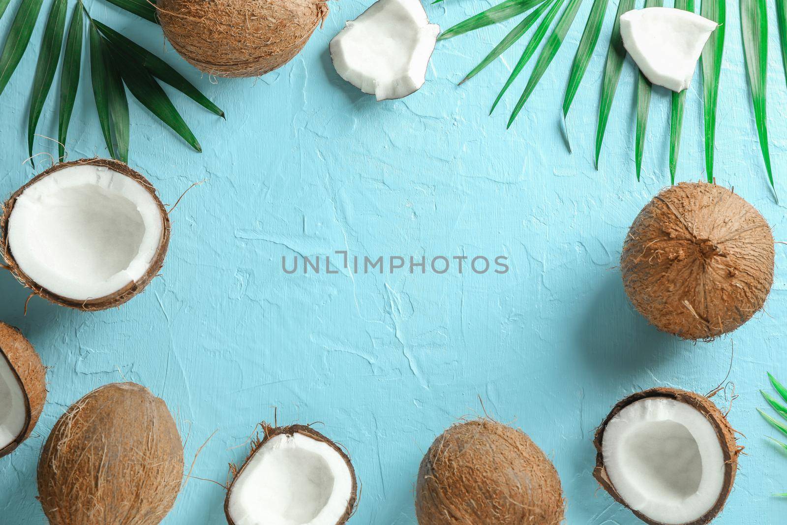 Tropical coconuts with palm branches on color background, space for text