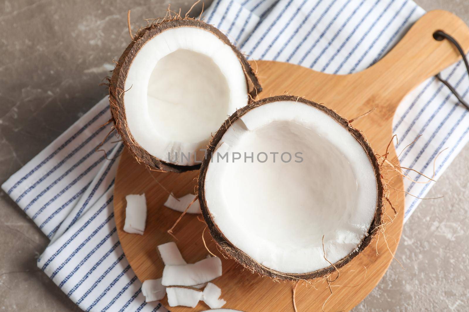 Cutting board with split coconut on table, space for text by AtlasCompany