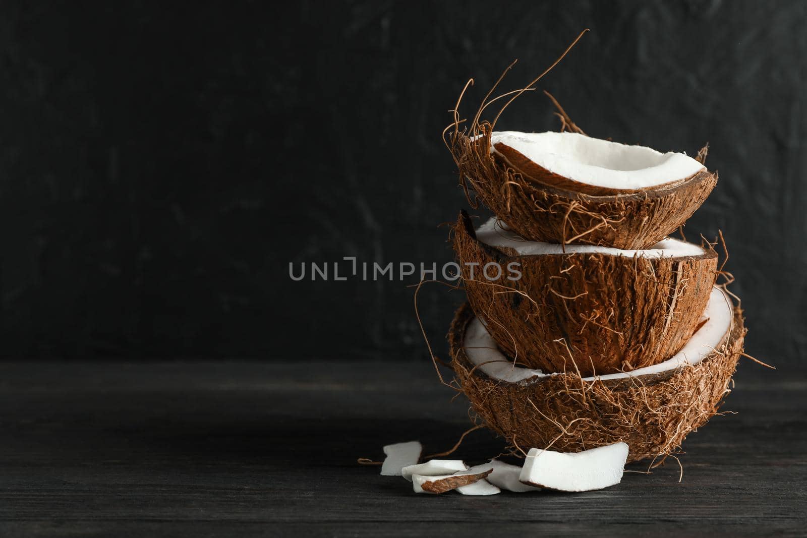 Stack tropical coconut on wooden table against black background, space for text by AtlasCompany