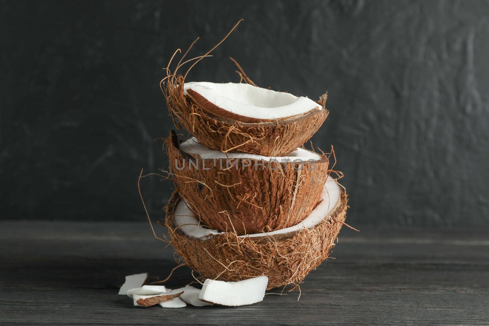 Stack tropical coconut on wooden table against black background, space for text