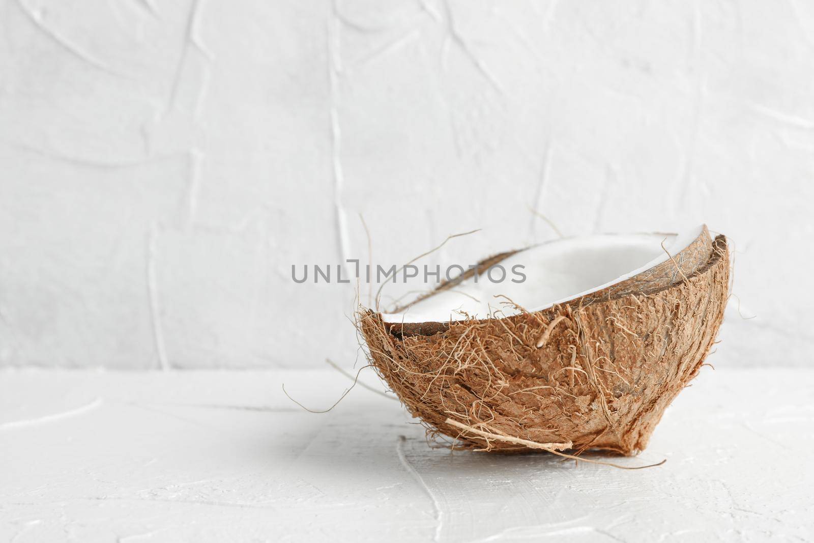 Half tropical coconut on wooden table against white background, space for text