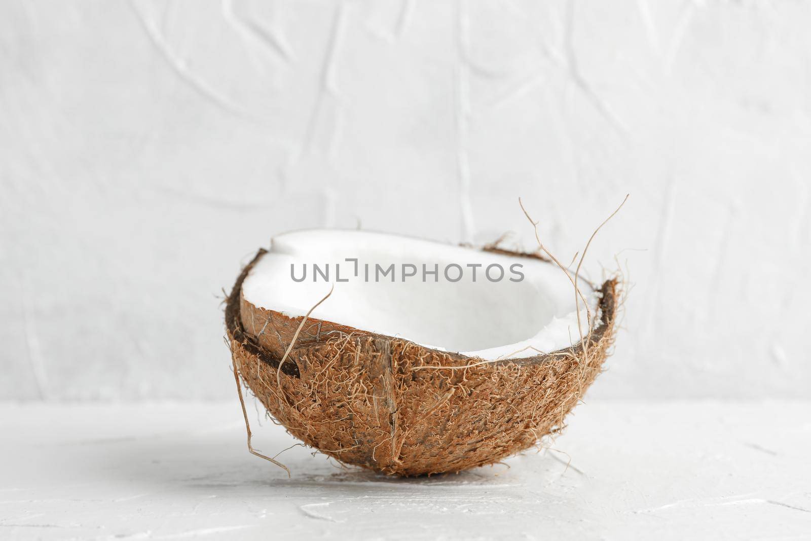 Half tropical coconut on wooden table against white background, space for text by AtlasCompany