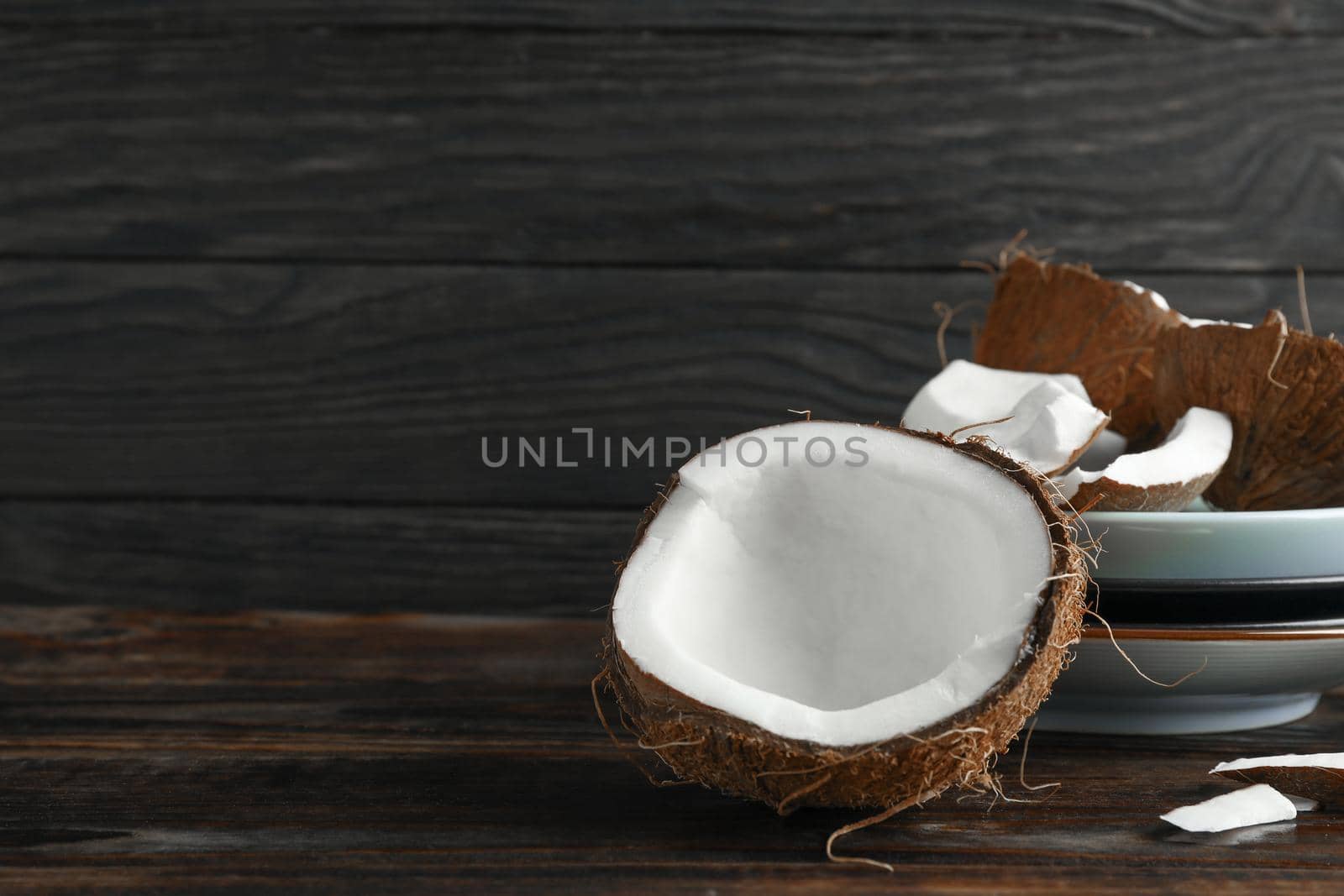 Coconuts on wooden table against dark background by AtlasCompany