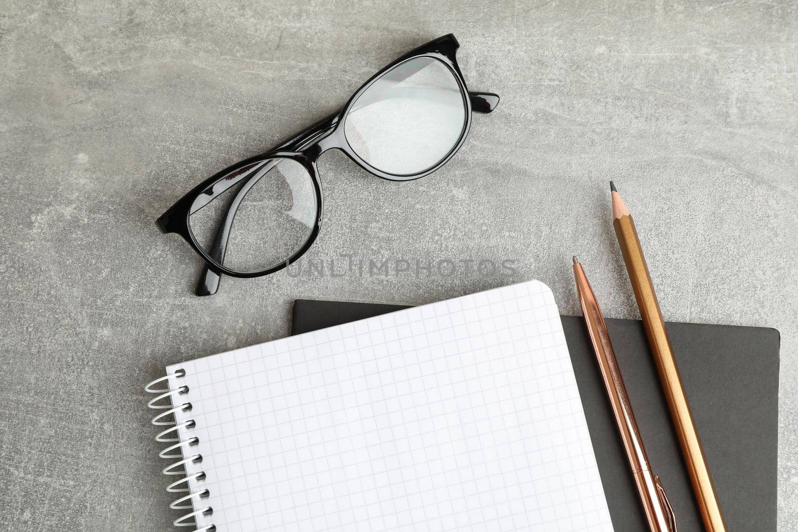 Copybooks, glasses and pencil on grey table, space for text