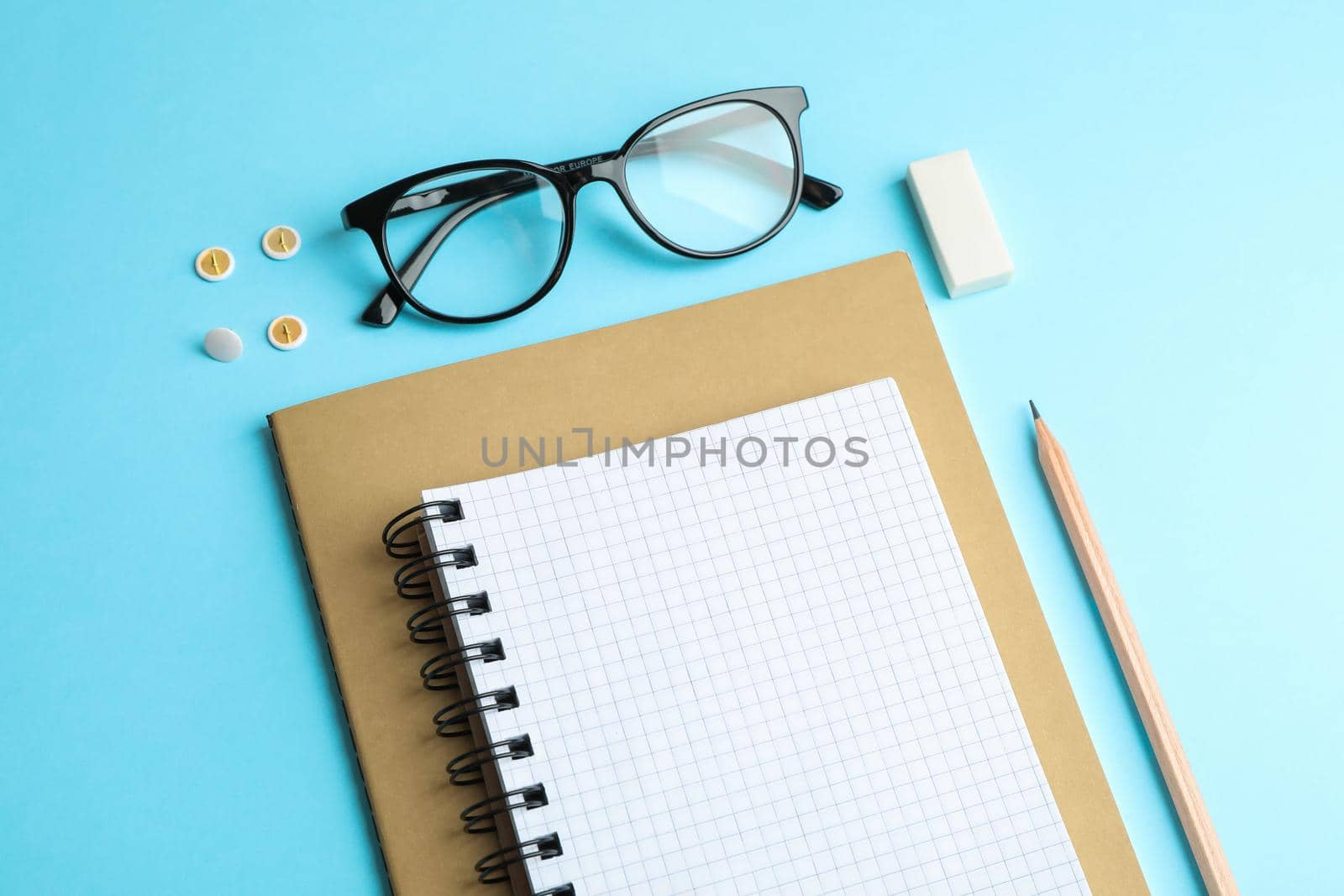 Copybooks, pencil and glasses on color background, space for text by AtlasCompany