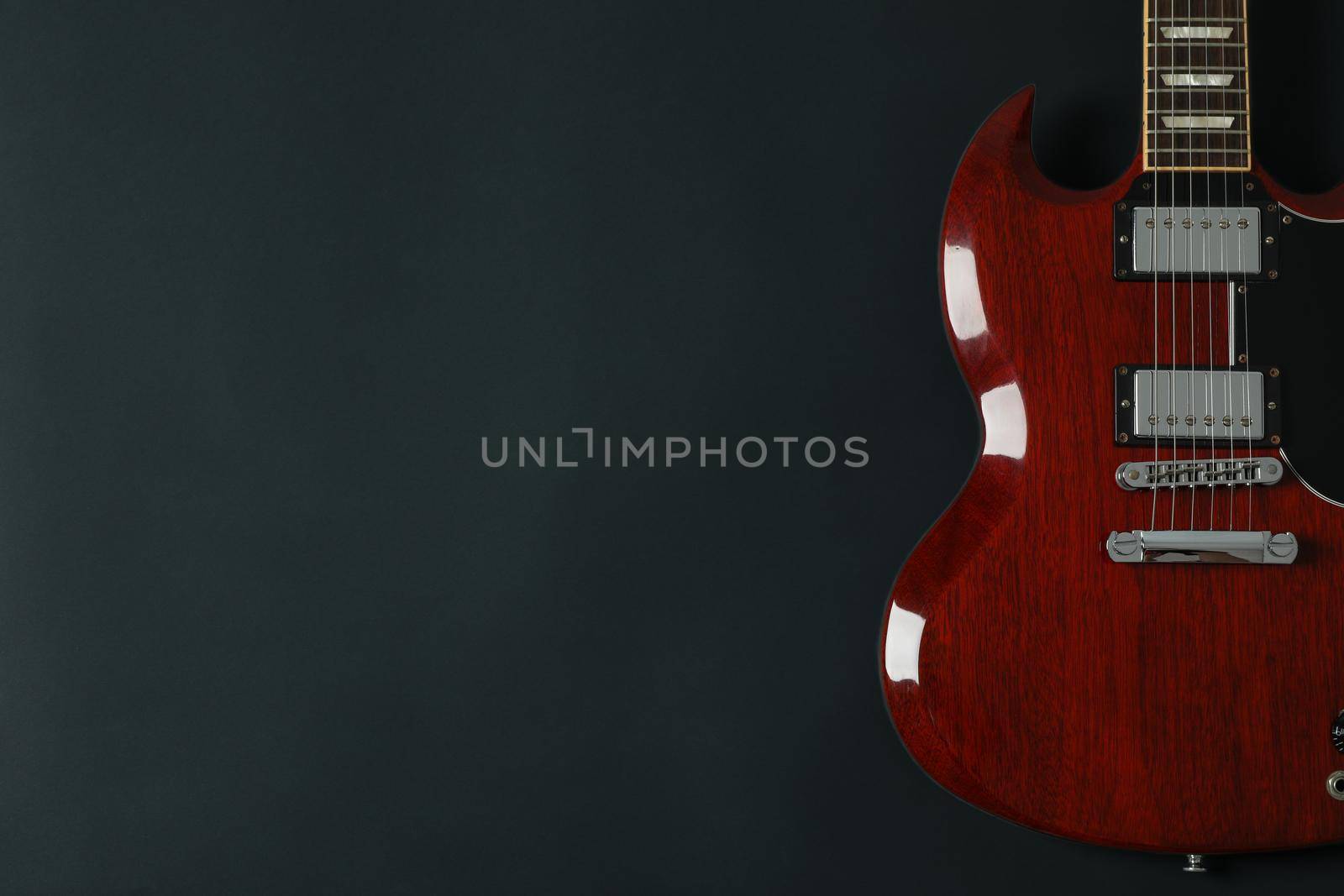 Beautiful six - string electric guitar on dark background, space for text