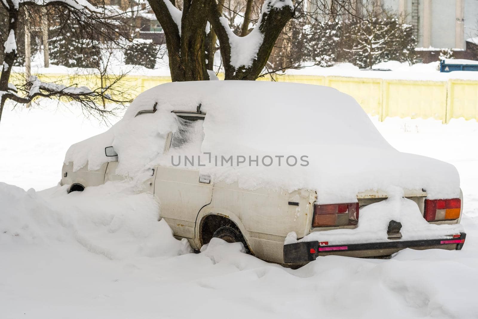 Stuck cars under the snow and ice. City street after blizzard. Buried vehicle in snowdrift on the road. Parking lots in winter after heavy snowfall. Uncleaned roads. Record-breaking amounts of snow.