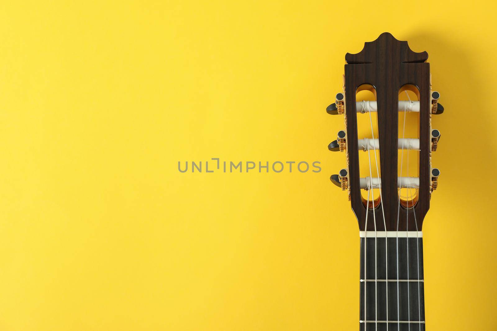 Guitar neck on yellow background, space for text