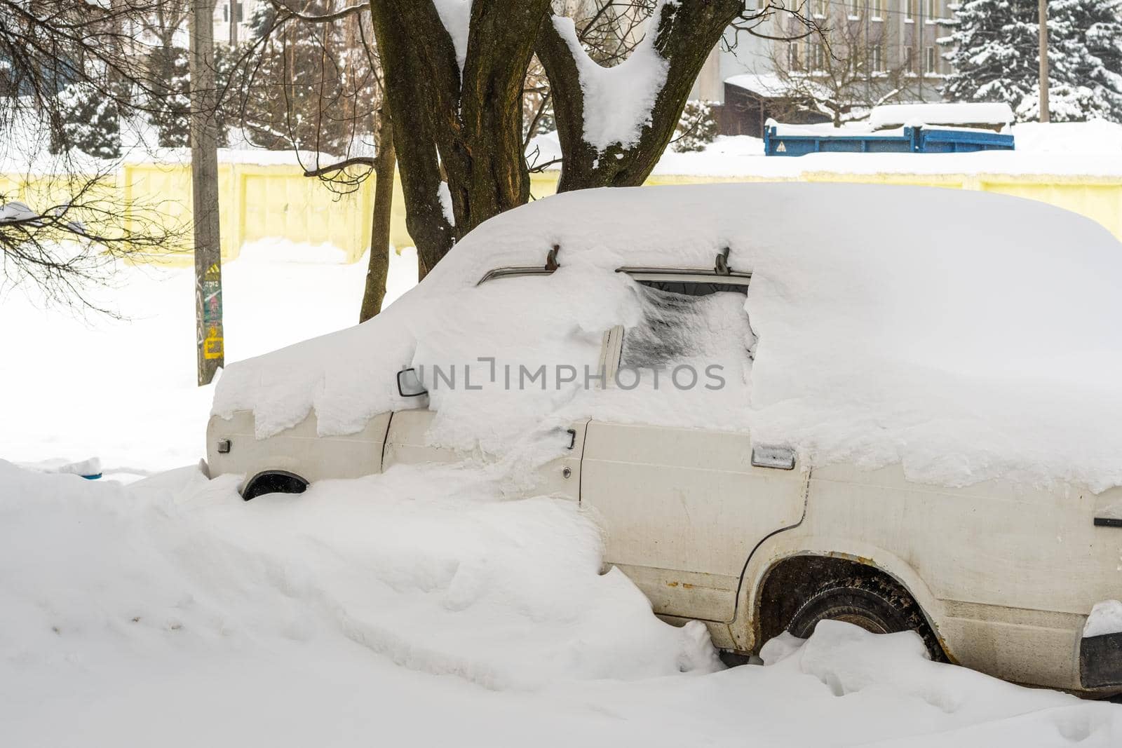 Stuck cars under the snow and ice. City street after blizzard. Buried vehicle in snowdrift on the road. Parking lots in winter after heavy snowfall. Uncleaned roads. Record-breaking amounts of snow.