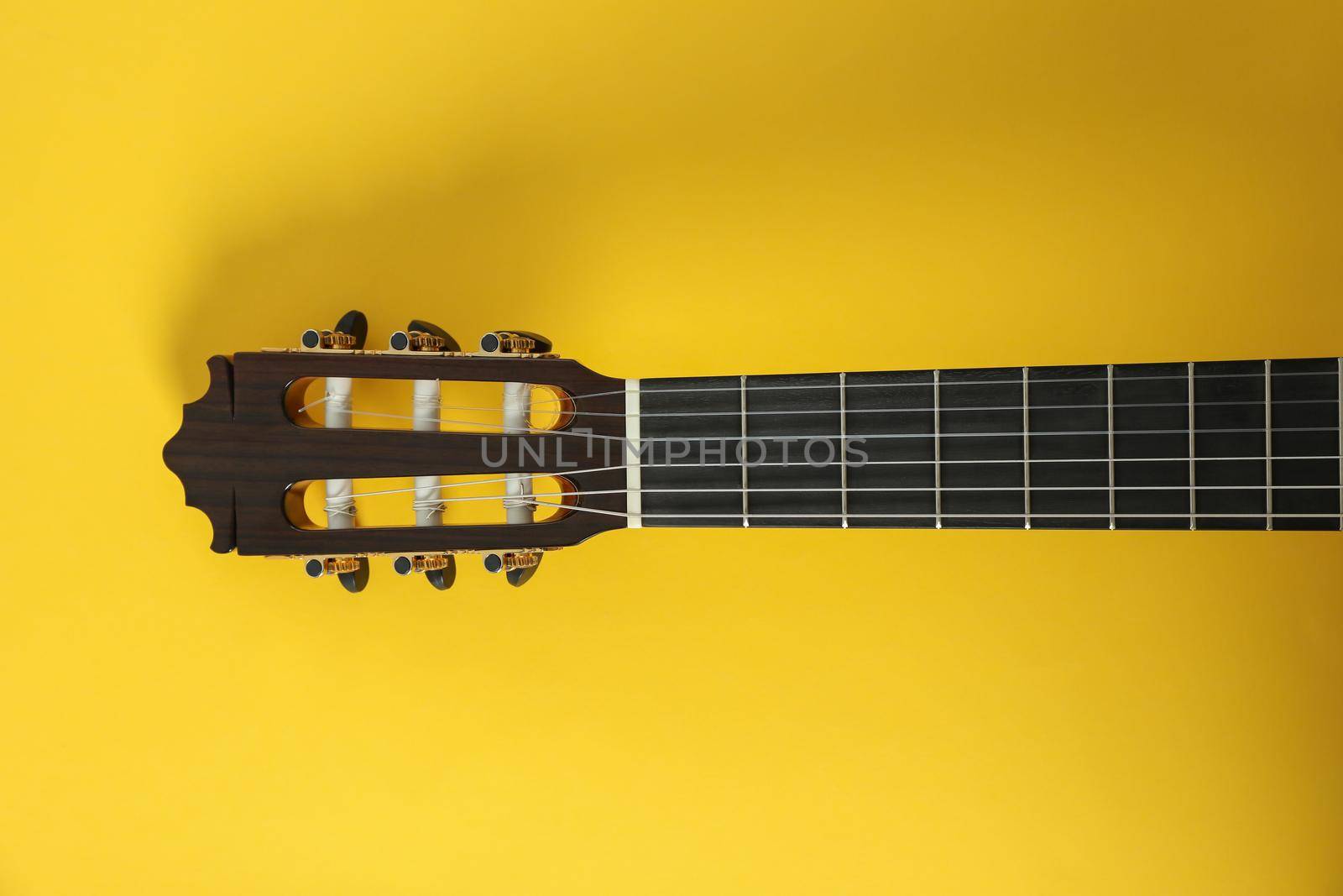 Guitar neck on yellow background, space for text