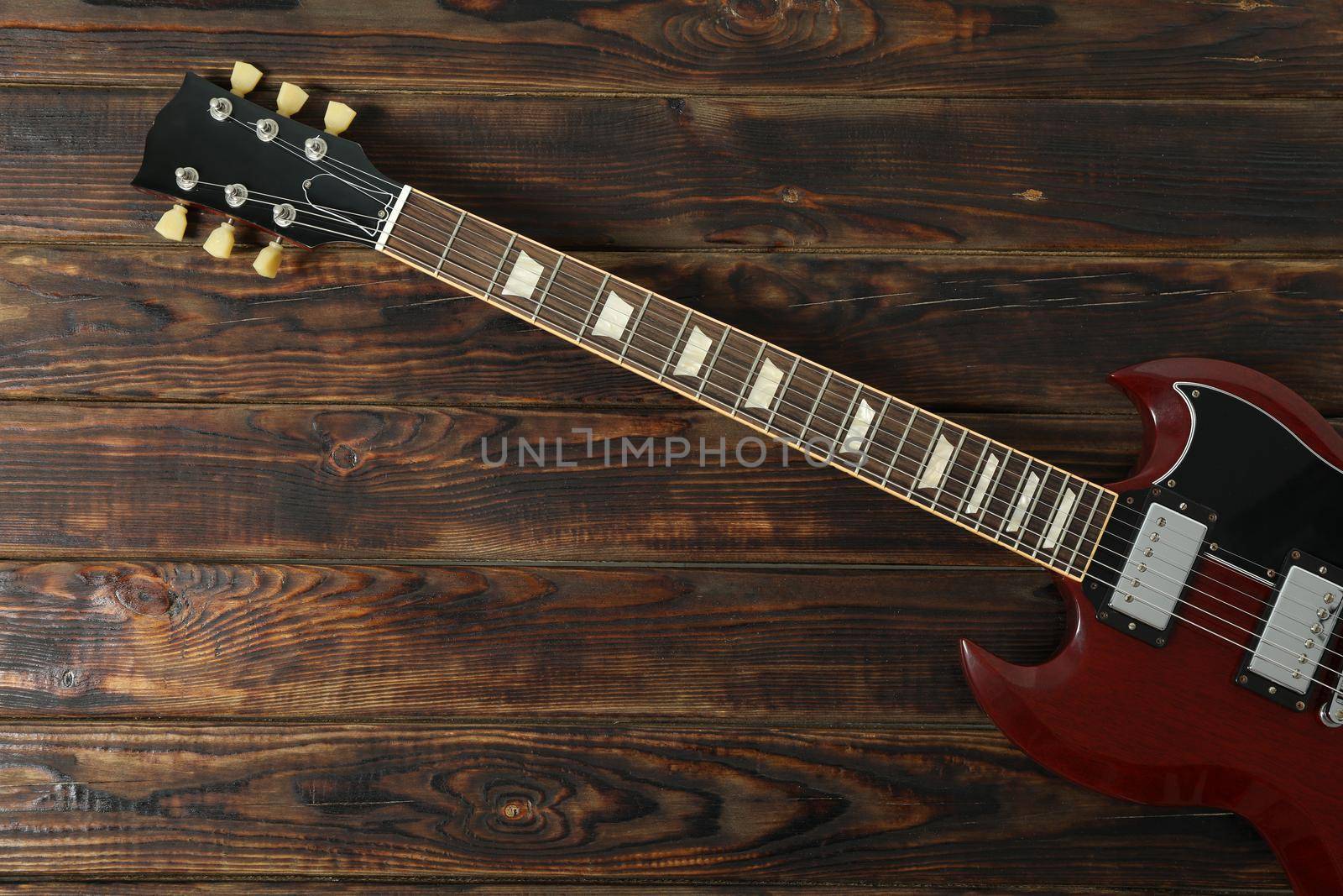 Beautiful six - string electric guitar on wooden background, space for text