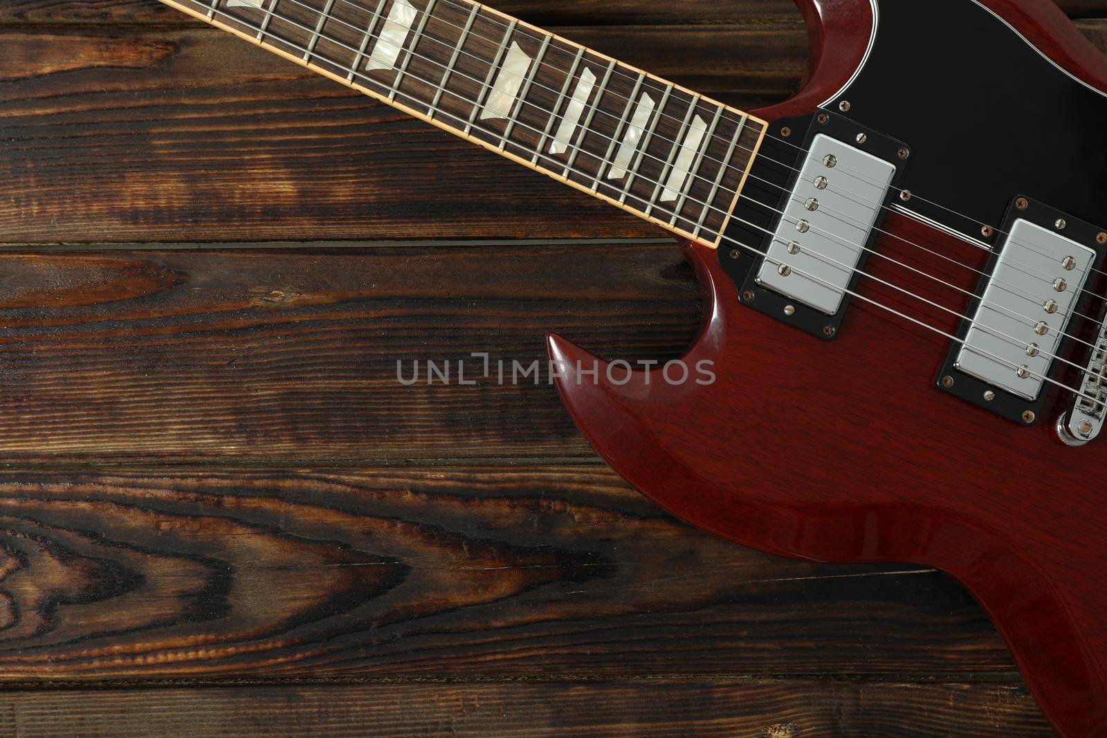 Beautiful six - string electric guitar on wooden background, space for text by AtlasCompany