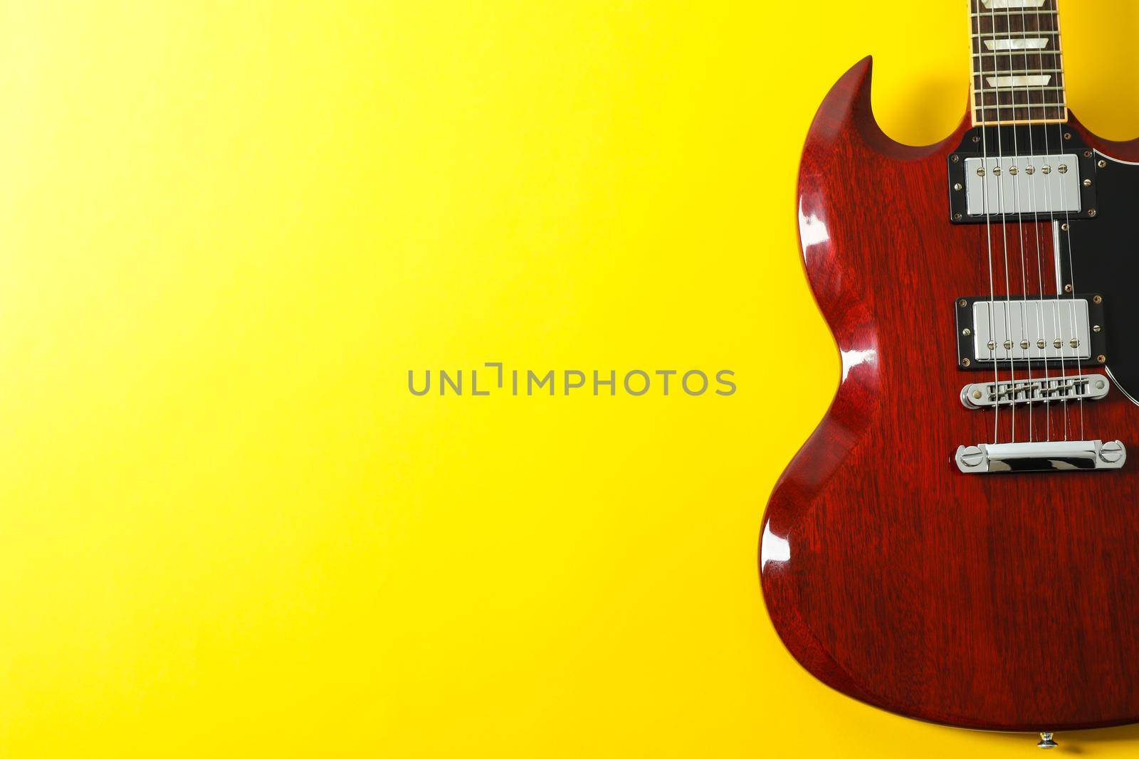 Beautiful electric guitar on yellow background, space for text