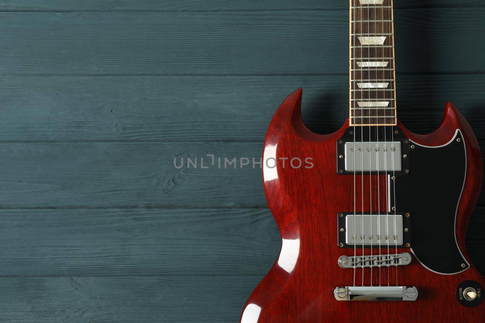 Beautiful six - string electric guitar on wooden background, space for text