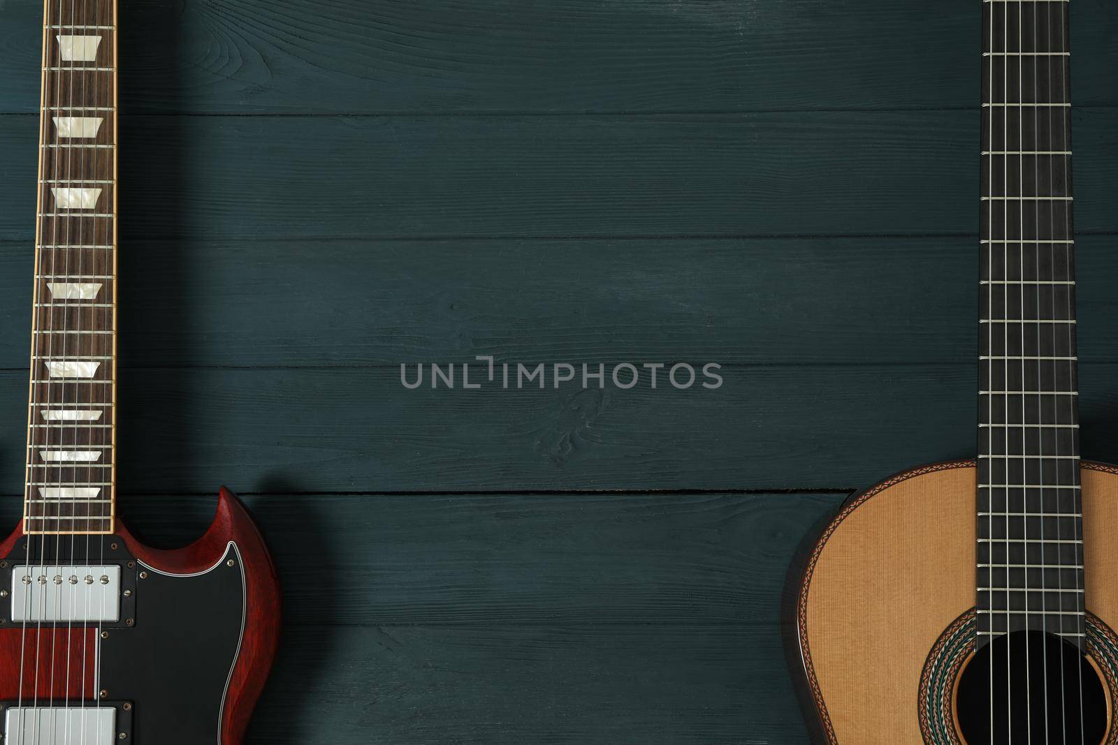 Electric and classic guitar on wooden background, space for text