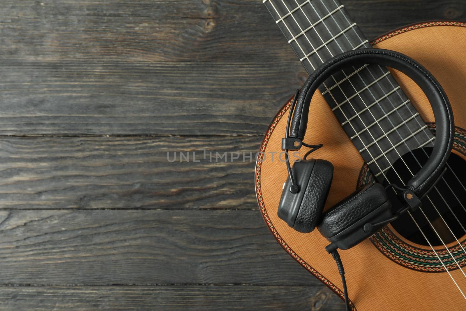 Beautiful classic guitar with headphones on wooden background, space for text by AtlasCompany