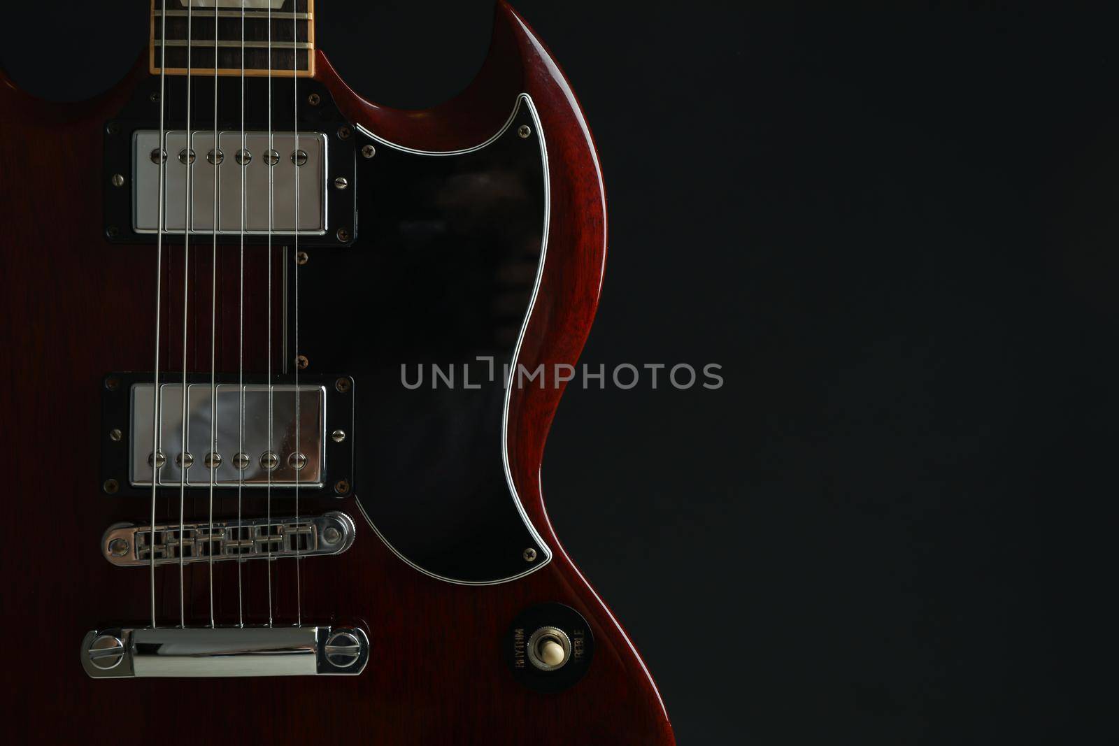 Beautiful six - string electric guitar against dark background, space for text