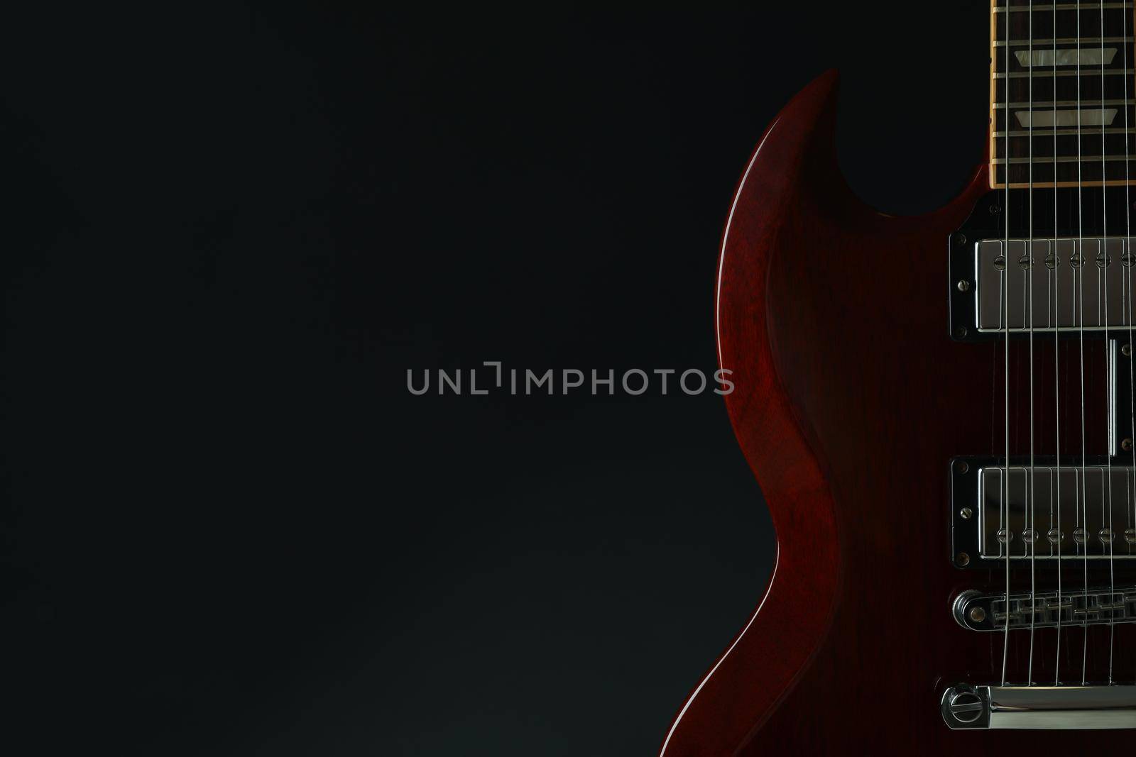 Beautiful six - string electric guitar against dark background, space for text