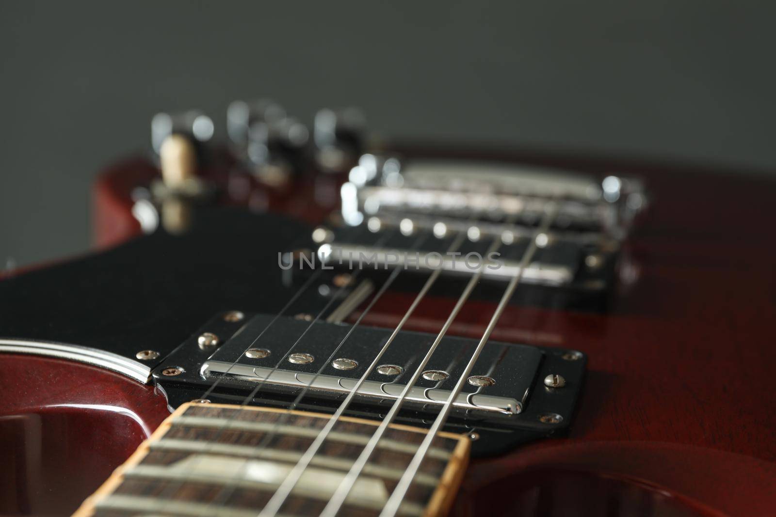 Beautiful six - string electric guitar against dark background, closeup