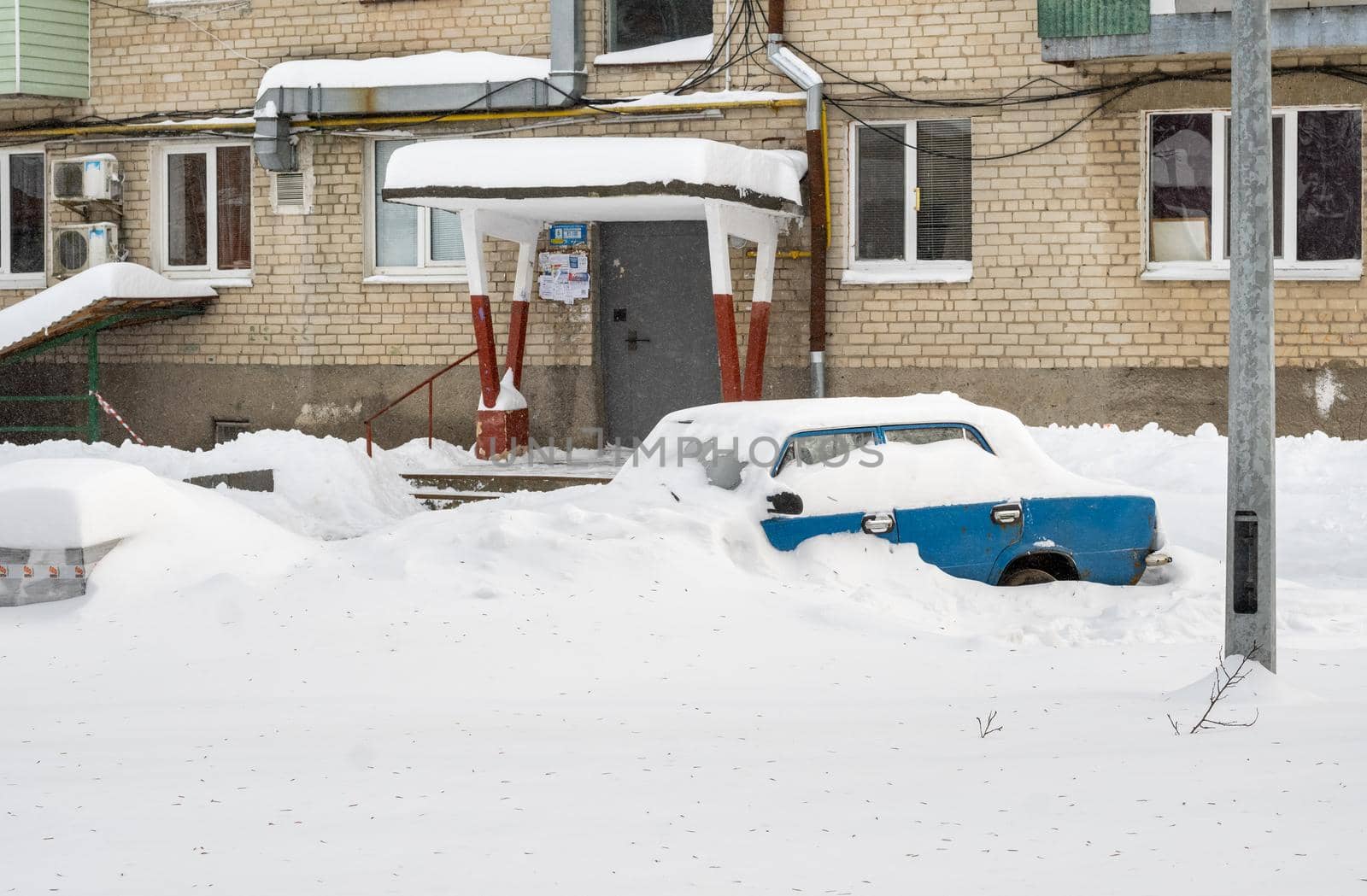 Stuck cars under the snow and ice. City street after blizzard. Buried vehicle in snowdrift on the road. Parking lots in winter after heavy snowfall. Uncleaned roads. Record-breaking amounts of snow.
