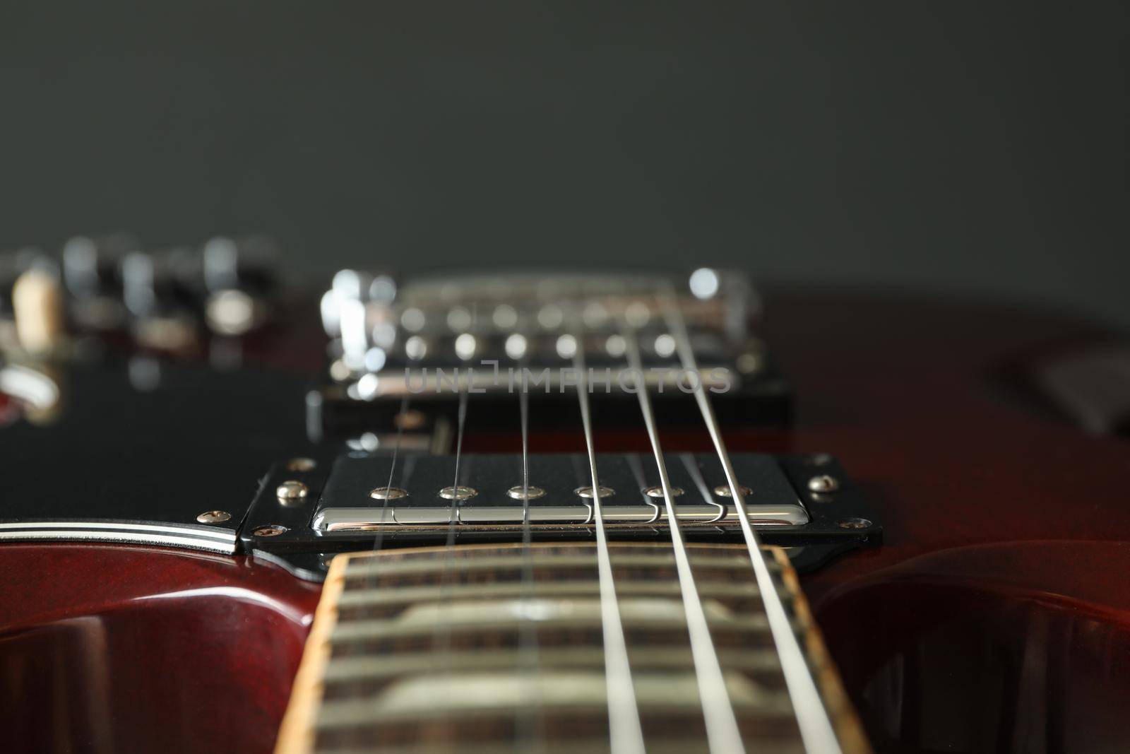 Beautiful six - string electric guitar against dark background, closeup