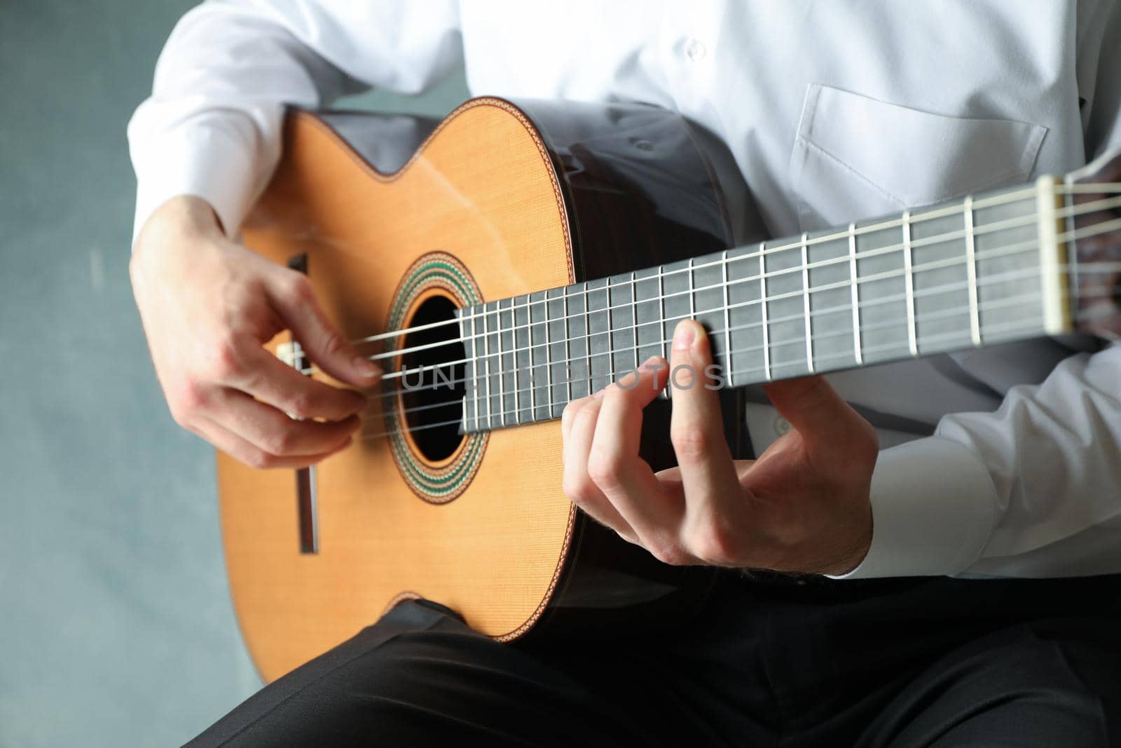 Man playing on classic guitar against light background, space for text