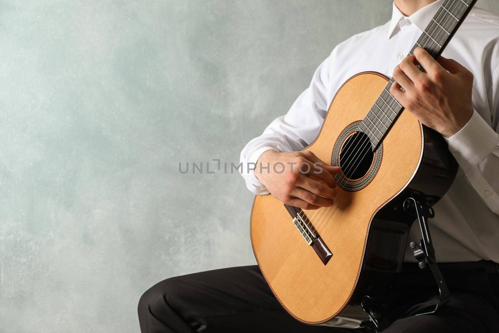 Man playing on classic guitar against light background, space for text by AtlasCompany