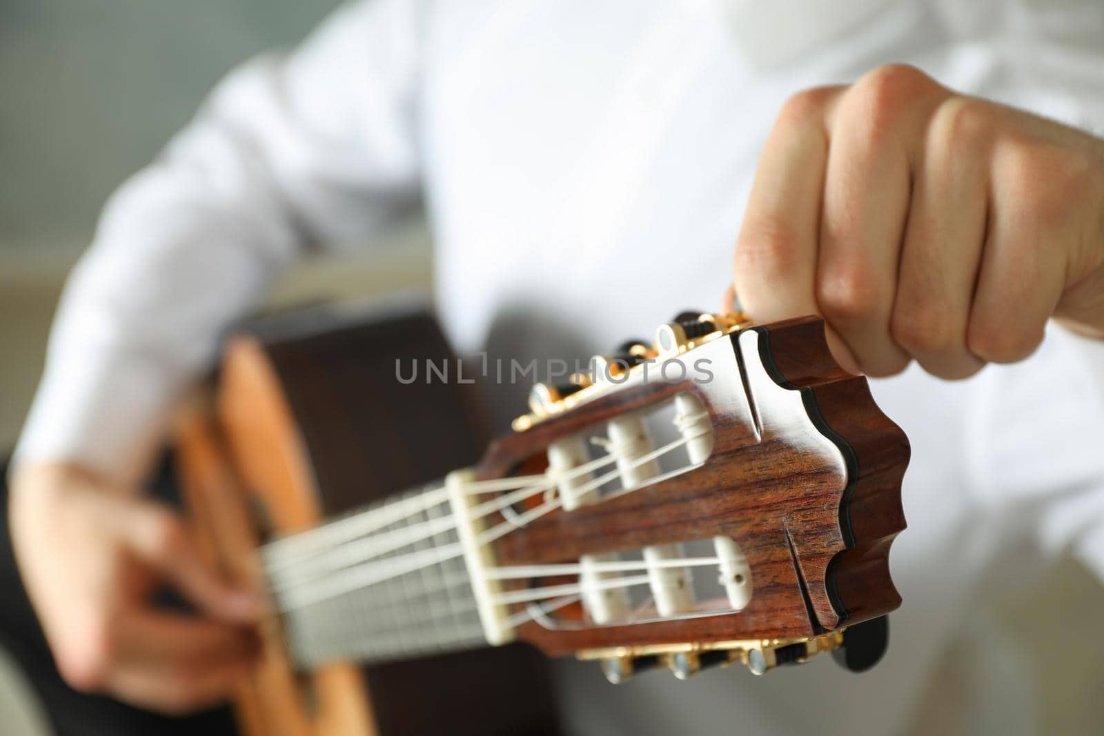 Man tunes classic guitar against dark background space for text