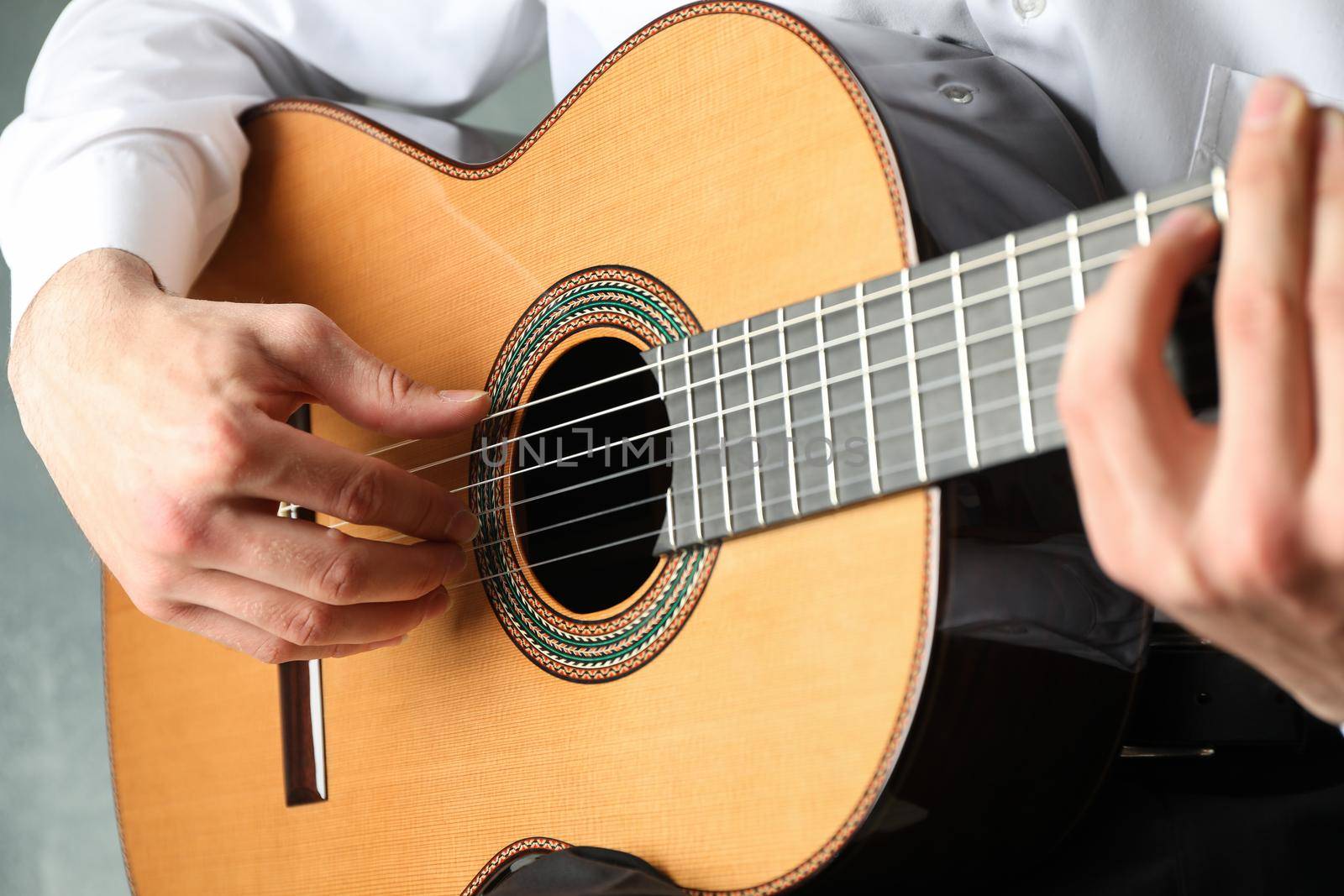 Man playing on classic guitar against light background, space for text