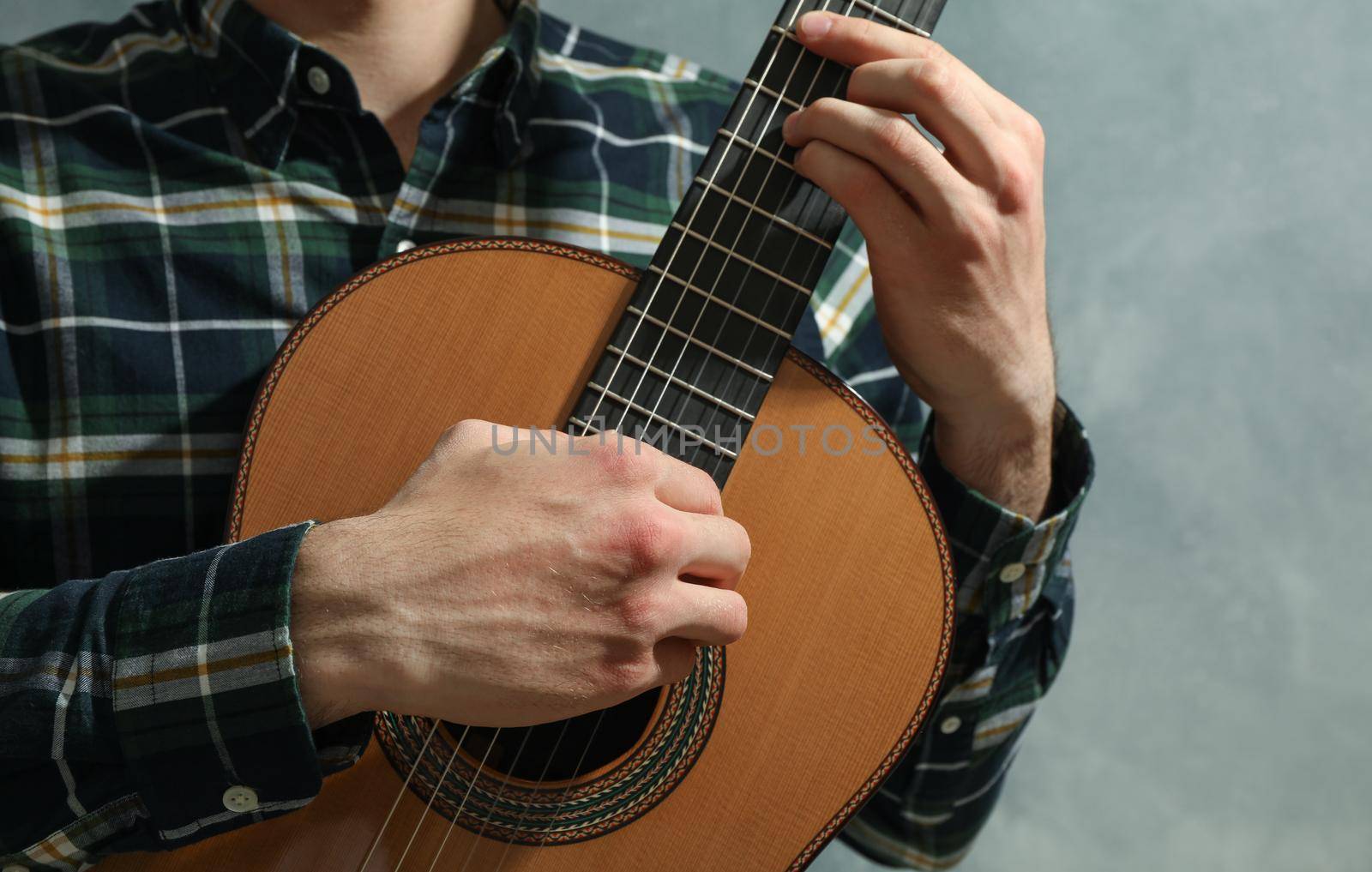 Man playing on classic guitar against light background