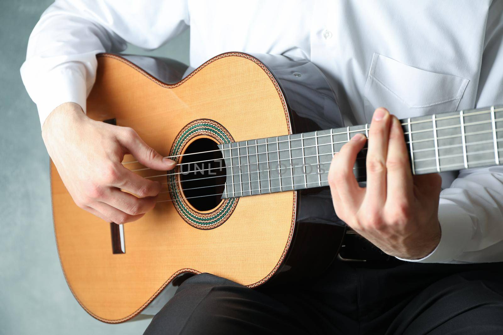 Man playing on classic guitar against light background, space for text by AtlasCompany