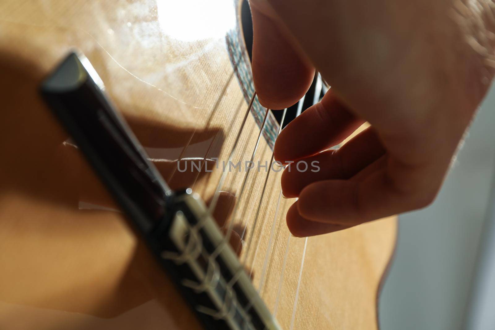 Man playing on classic guitar against light background, closeup by AtlasCompany