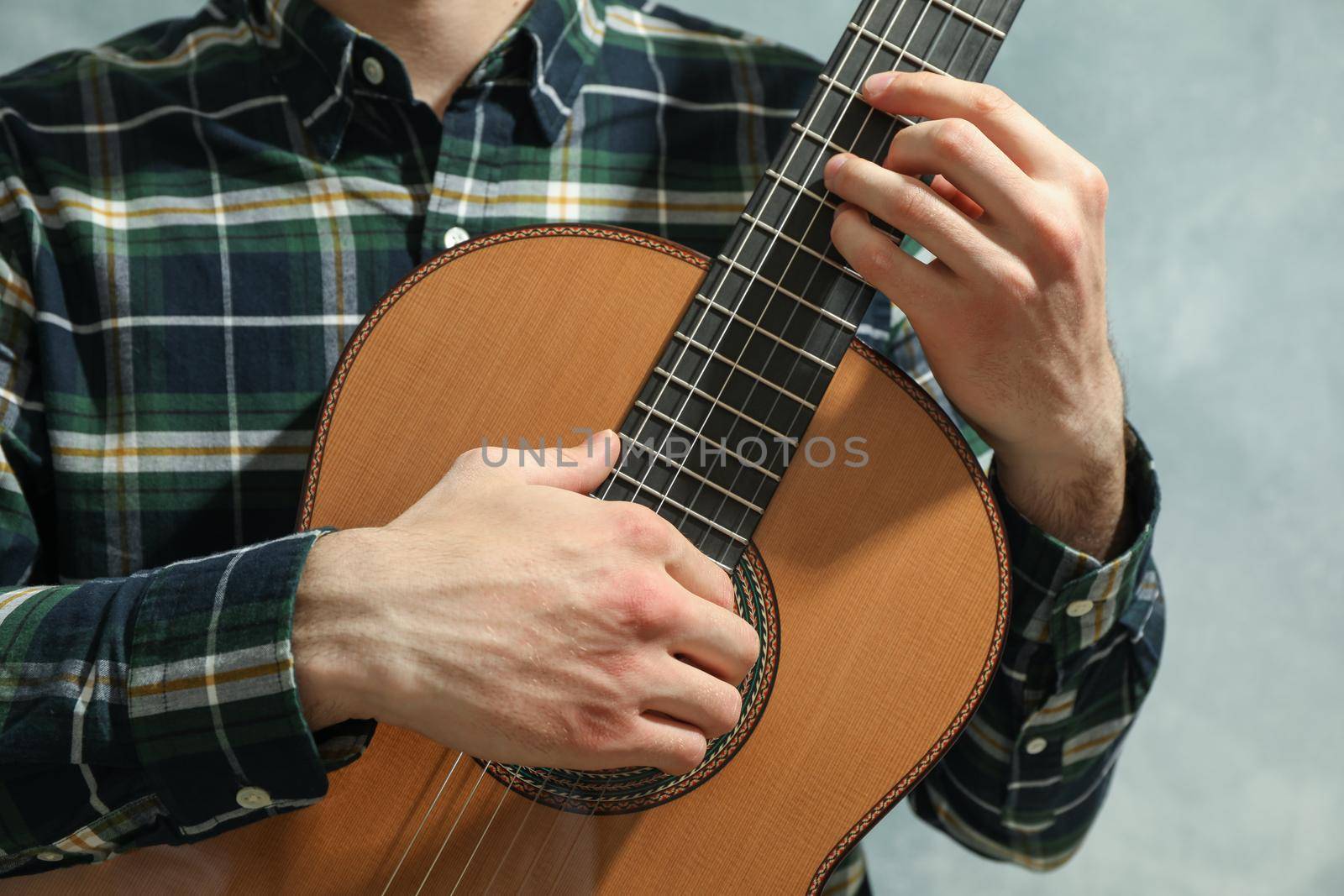 Man playing on classic guitar against light background by AtlasCompany