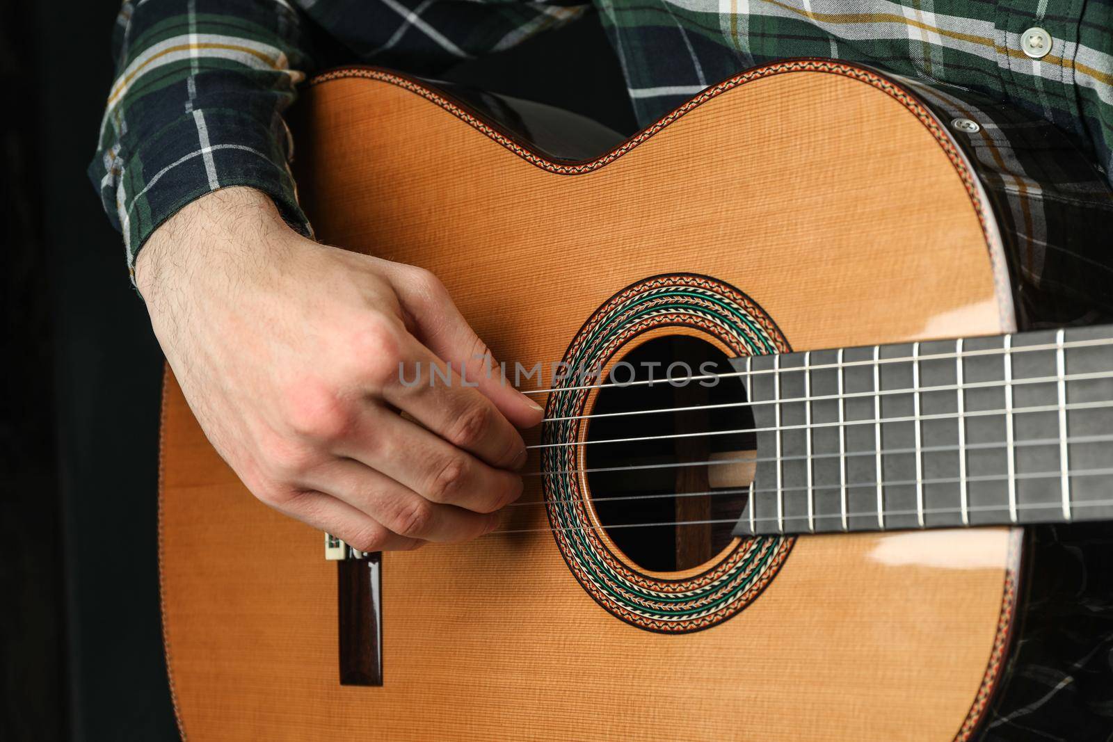 Man playing on classic guitar against dark background, space for text