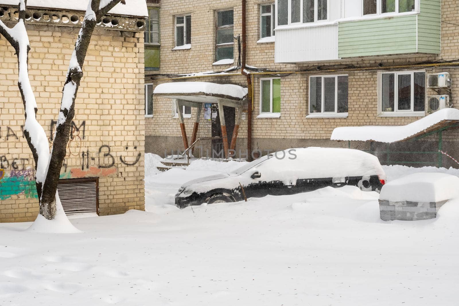 Stuck cars under the snow and ice. City street after blizzard. Buried vehicle in snowdrift on the road. Parking lots in winter after heavy snowfall. Uncleaned roads. Record-breaking amounts of snow.