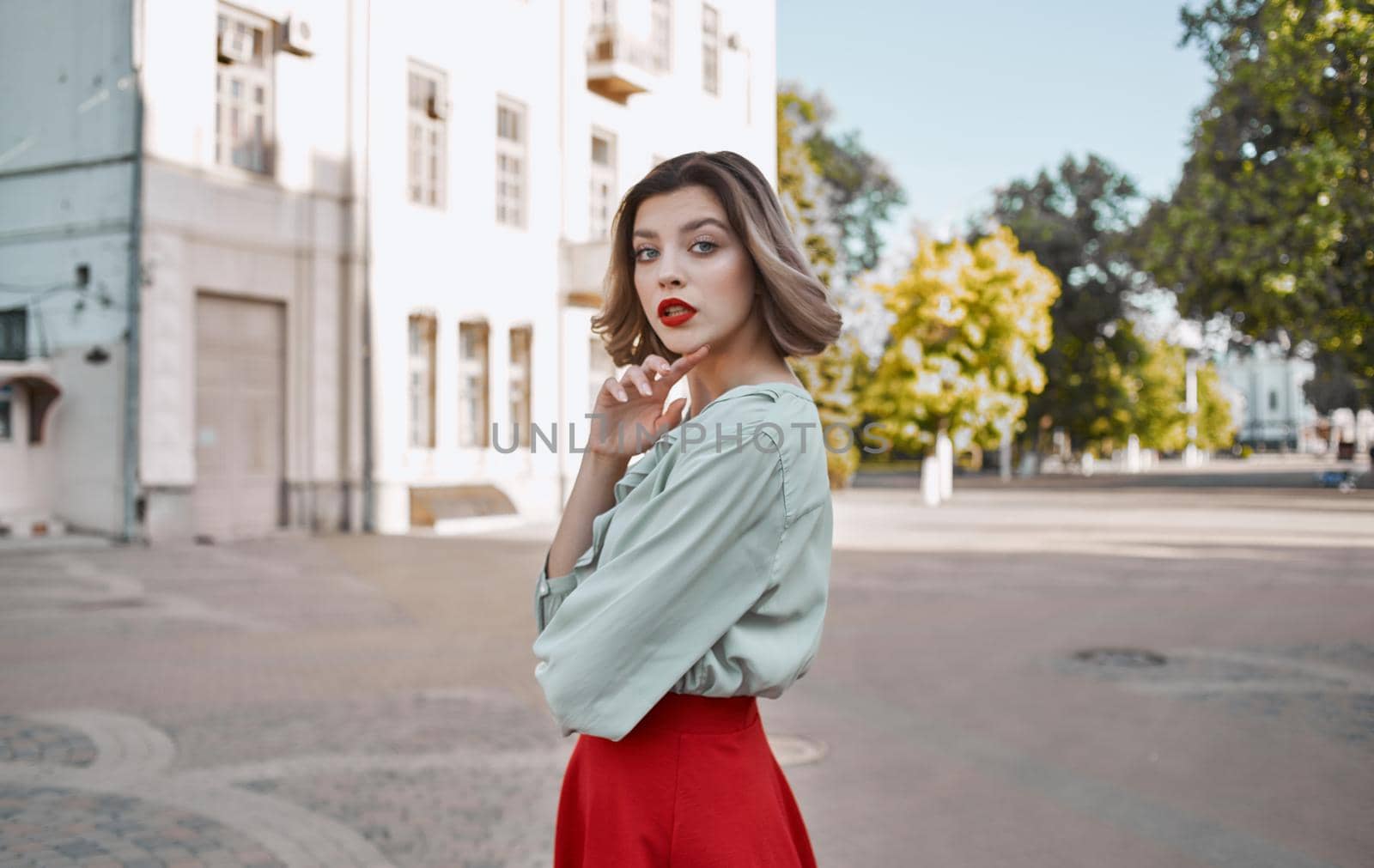 woman with bright makeup in a shirt and in a red skirt are walking on the street in summer near the building. High quality photo