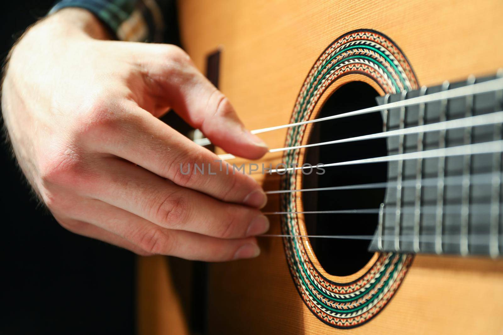 Man playing on classic guitar against dark background, closeup by AtlasCompany