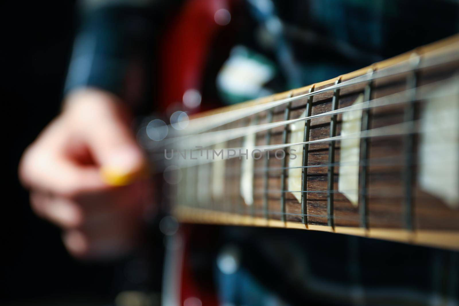 Man playing on electric guitar against dark background, closeup by AtlasCompany