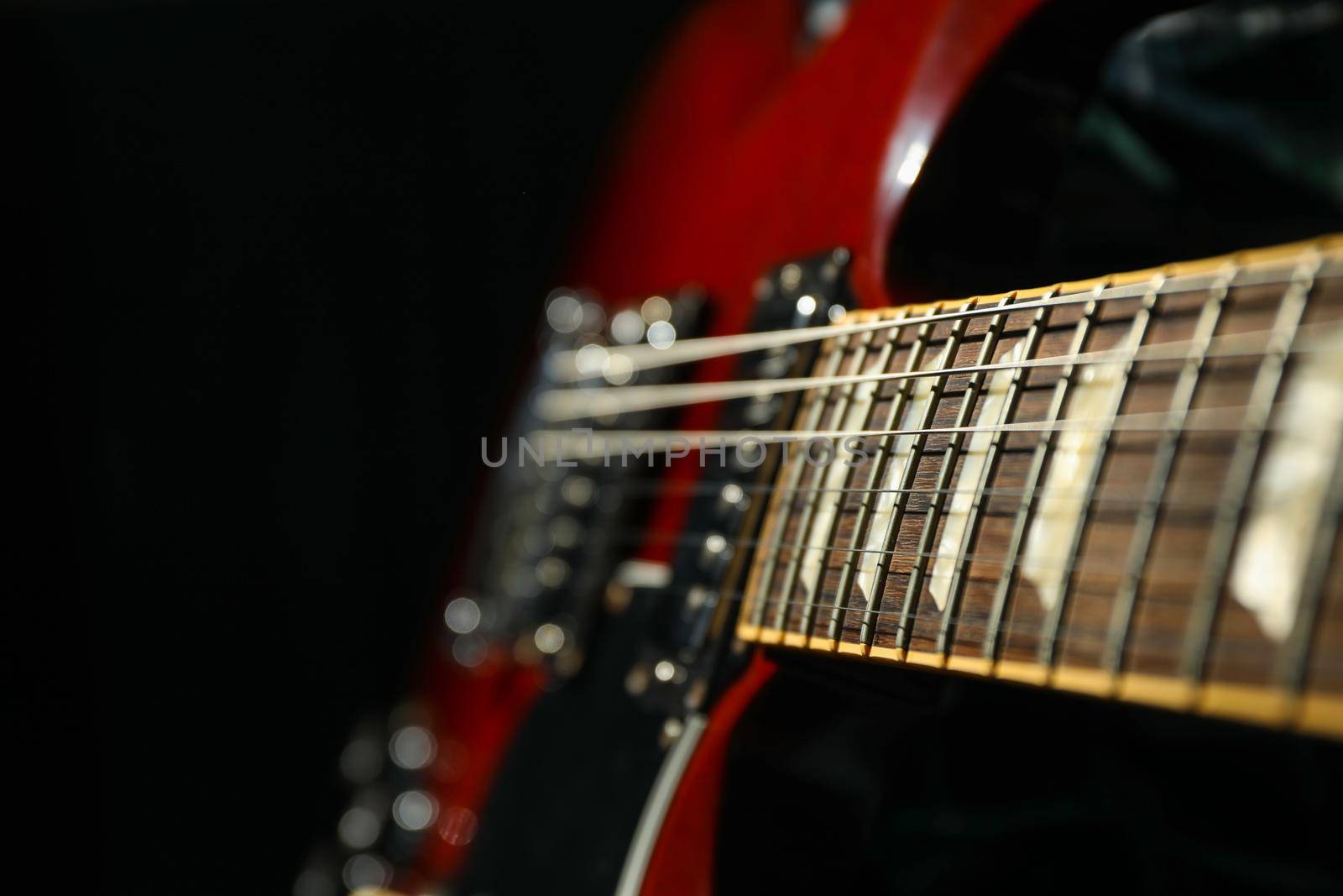 Beautiful six - string electric guitar against dark background, closeup by AtlasCompany