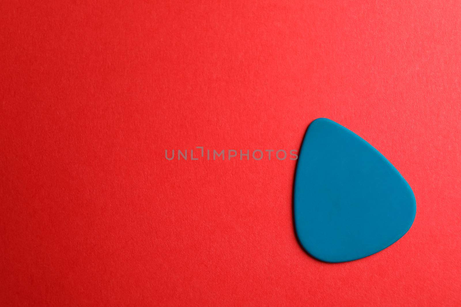 Blue guitar pick on color background, space for text