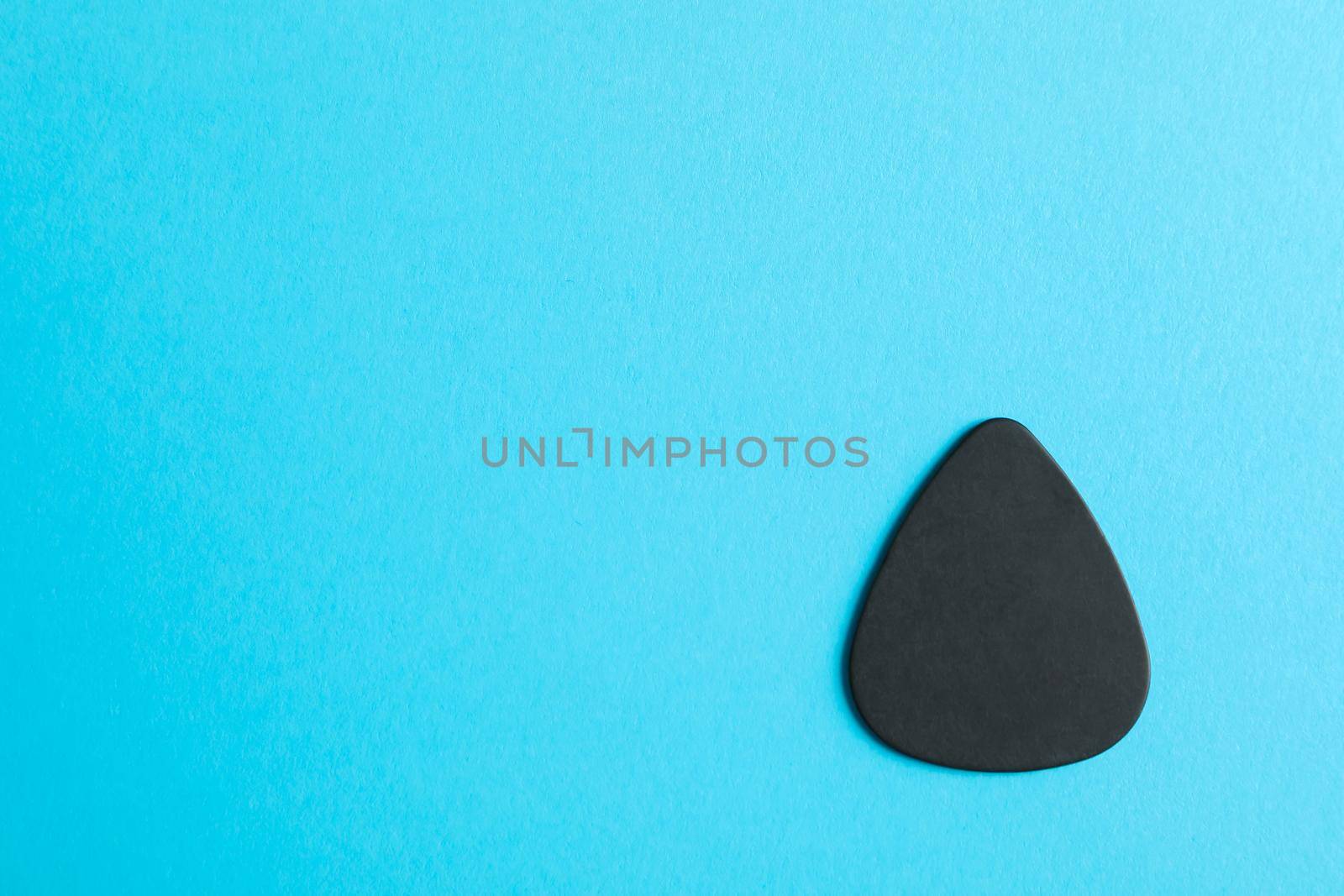 Black guitar pick on color background, space for text