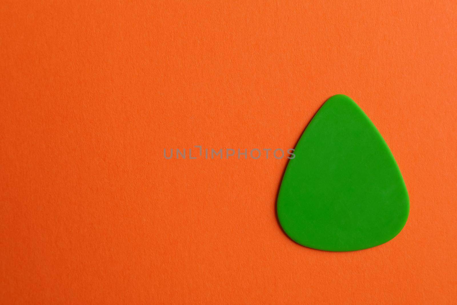 Green guitar pick on color background, space for text by AtlasCompany