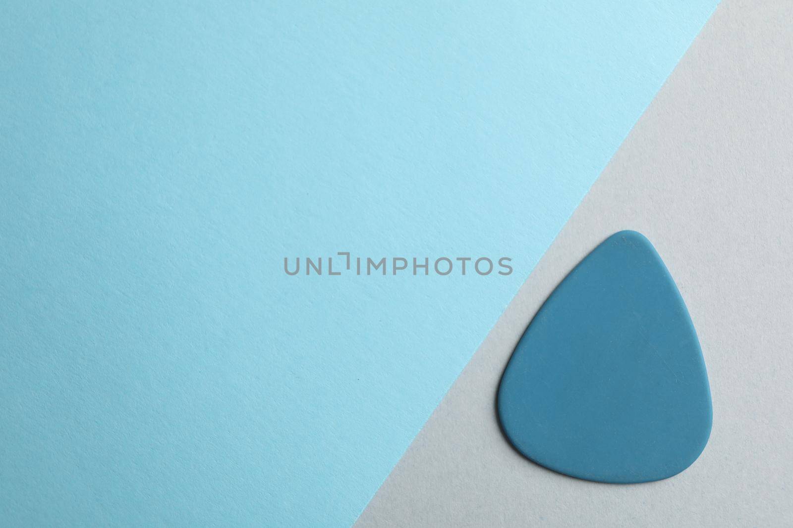 Blue guitar pick on two tone background, space for text