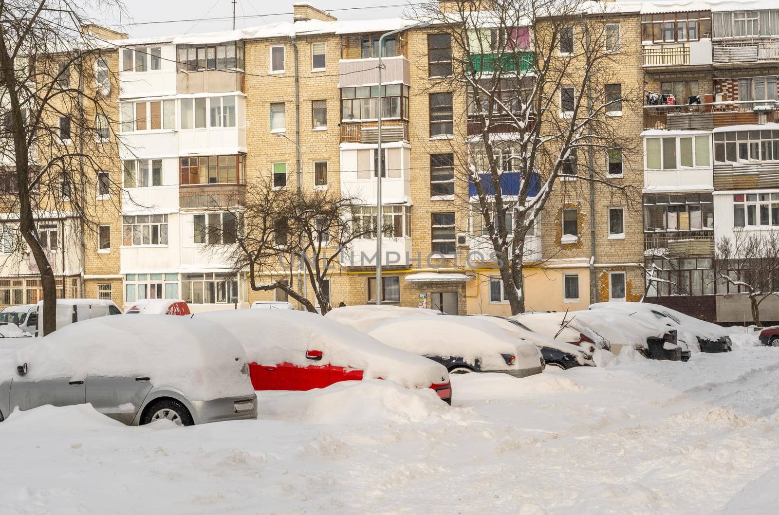Stuck cars under the snow and ice. City street after blizzard. Buried vehicle in snowdrift on the road. Parking lots in winter after heavy snowfall. Uncleaned roads. Record-breaking amounts of snow.