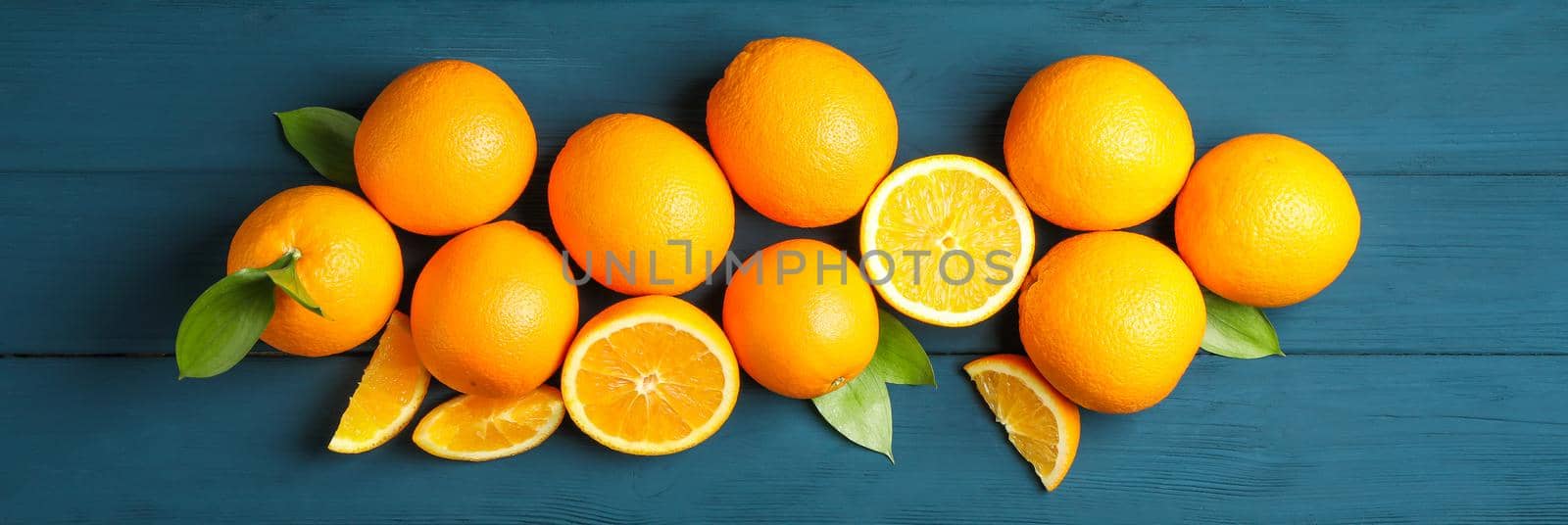 Flat lay composition with ripe oranges and leaves on wooden background. Top view