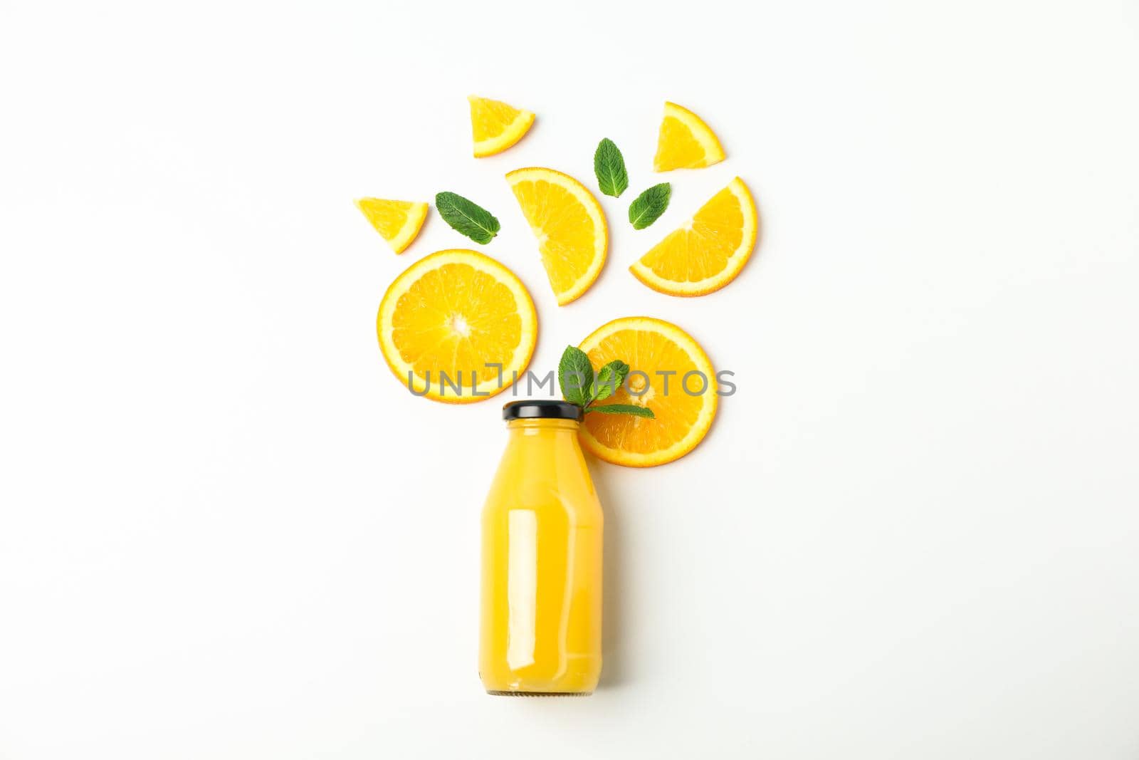 Flat lay composition with orange juice in bottle, orange pieces and mint on white background, space for text. Natural drinks and fruits by AtlasCompany