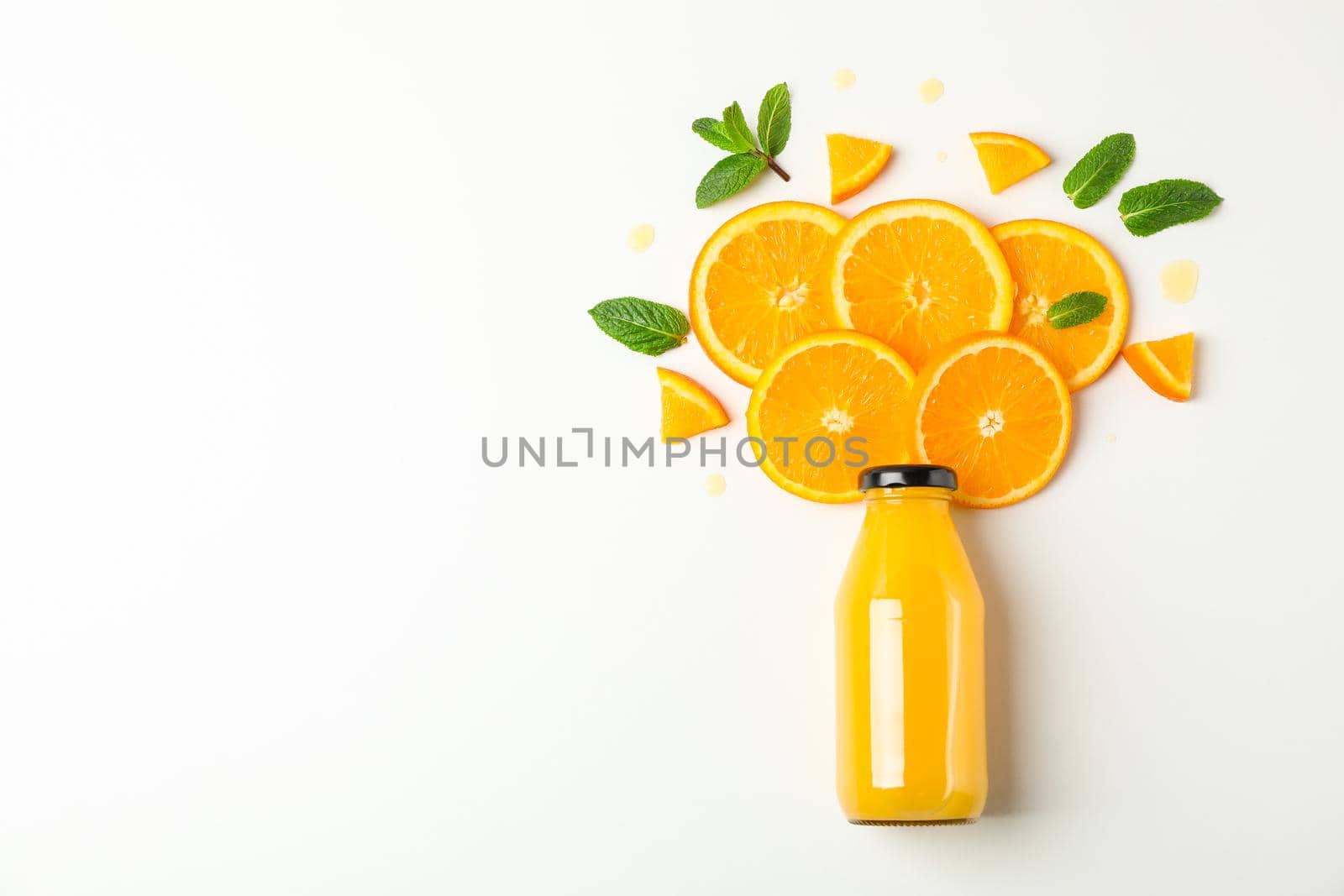 Flat lay composition with orange juice in bottle, orange pieces and mint on white background, space for text. Citrus drink and fruits by AtlasCompany